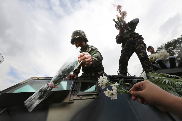 FLOWER POWER Soldiers on an armored vehicle receive flowers from civilians taking part in the commemoration of the 30th anniversary of the Edsa People Power Revolution on Thursday, in a reenactment of the peaceful uprising in 1986. JOAN BONDOC