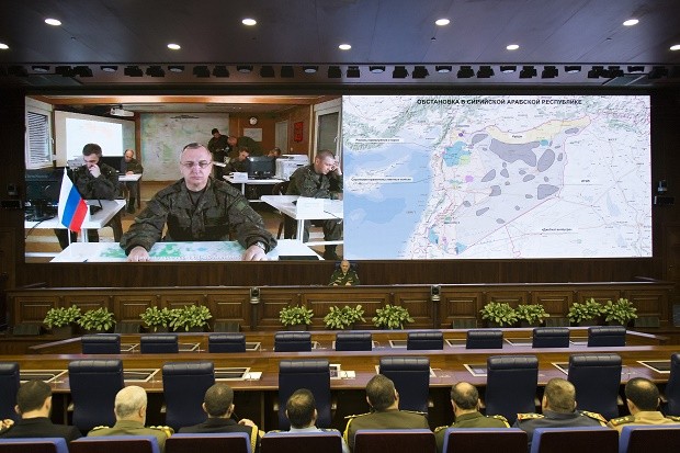 Lt.-Gen. Sergei Rudskoi of the Russian Military General Staff, background center, speaks to the media in Moscow, Russia, Saturday, Feb. 27, 2016. A top military official says Russia has halted all airstrikes in areas of Syria where armed groups, including government forces, said they would abide by a cease-fire. The screen shows, at left, Lt.-Gen. Sergei Kuralenko at Hemeimeem airbase in Syria. (AP Photo/Alexander Zemlianichenko)