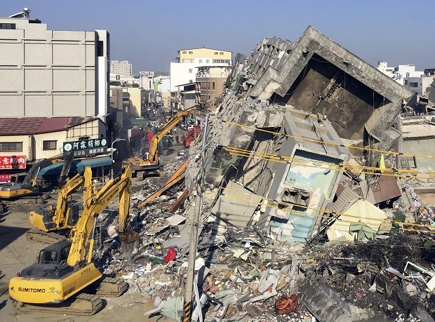Rescue workers using excavators continue to search the rubble of a collapsed building complex in Tainan, Taiwan, Tuesday, Feb. 9, 2016. At least four people, including an 8-year-old girl, were rescued Monday from a high-rise Taiwanese apartment building toppled by a powerful quake two days earlier, as frustration grew among families waiting for searchers to reach their buried loved ones. (AP Photo/Annie Ho)