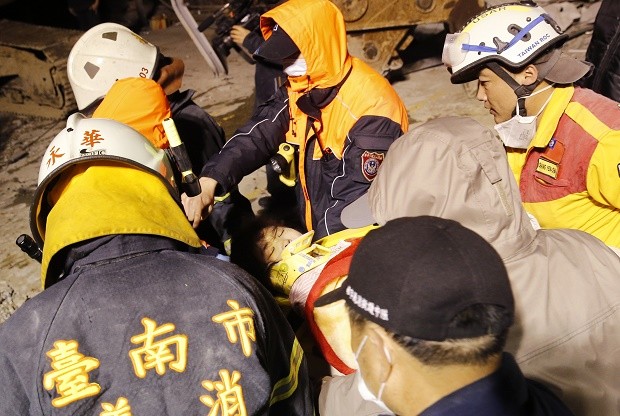 A woman is rescued from the rubble of a collapsed building complex from an early morning earthquake in Tainan, Taiwan, Saturday, Feb. 6, 2016. A powerful, shallow earthquake struck southern Taiwan before dawn Saturday. (AP Photo/Wally Santana)