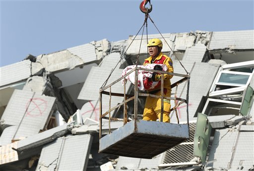 An emergency worker carries a rescued six month old baby girl from the rubble of a collapsed building in Tainan, Taiwan, Sunday, Feb. 7, 2016. Rescuers on Sunday found signs of live within the remains of a high-rise residential building that collapsed in a powerful, shallow earthquake in southern Taiwan that killed over a dozen people and injured hundreds. (AP Photo/Wally Santana)