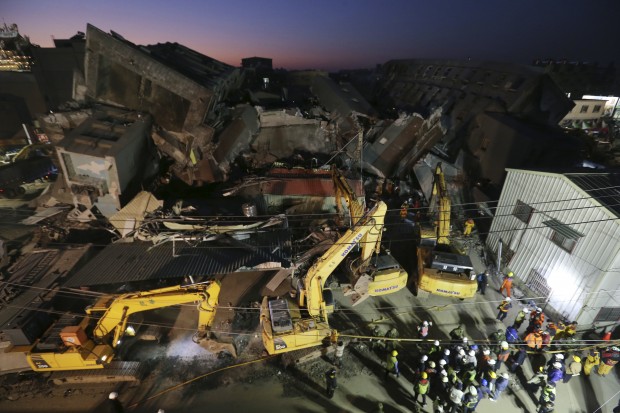 As night falls, emergency rescue workers continue to search the rubble of a collapsed building complex in Tainan, Taiwan, Monday, Feb. 8, 2016. More than 100 people are believed to still be under the debris in a powerful quake that struck on Saturday, Feb. 6, during the most important family holiday in the Chinese calendar — the Lunar New Year.(AP Photo) TAIWAN OUT