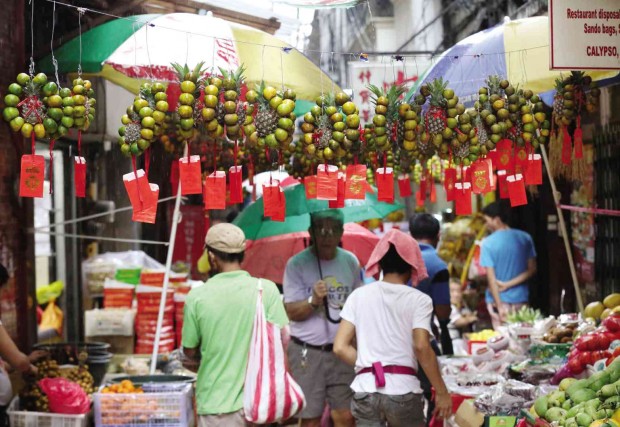 ROWS of kiat kiat “wreaths,” with a pineapple in the center, adorn stalls lining a street in Binondo, Manila. Eating and displaying these fruits is believed to bring in good luck for the Year of the Fire Monkey.  MARIANNE BERMUDEZ