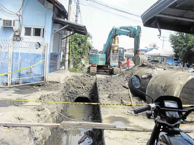 A BACKHOE helps dig up a drain that would lead to an oil pipeline that had suffered a leak, releasing foul odor in the town of Dinalupihan in Bataan province.             GREG REFRACCION/INQUIRER CENTRAL LUZON