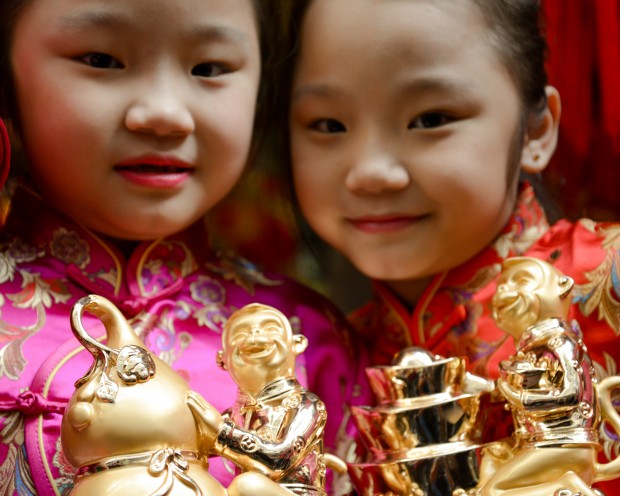 LUCKY CHARMS Chinese twins Trixia and Trixie hold monkey figurines in Ongpin, Binondo a day before the Chinese New Year. INQUIRER PHOTO / ELOISA LOPEZ