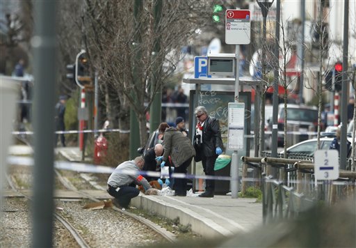 Investigators collect evidence near a tram track in Schaerbeek, Belgium, Friday March 25, 2016. A witness speaking on Belgian state broadcaster RTBF described hearing two blasts and shots from heavy weapons during the police raid on the Schaerbeek neighborhood. About 50 officers appeared to be involved in the operation. It is unclear whether it is linked to Tuesday's attacks. A tram passing through the area was stopped and evacuated and police cordoned off a wide perimeter of streets. (AP Photo/Alastair Grant)