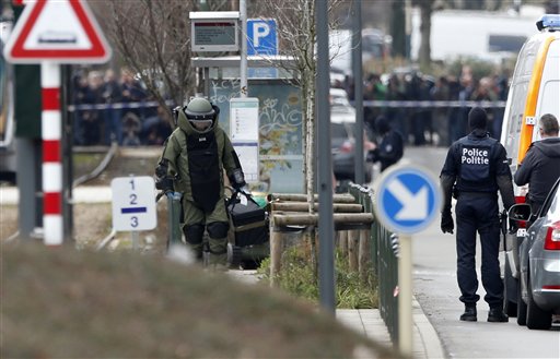 A member of emergency services wearing protective clothing investigates the scene in Schaerbeek, Belgium, Friday March 25, 2016. A witness speaking on Belgian state broadcaster RTBF described hearing two blasts and shots from heavy weapons during the police raid on the Schaerbeek neighborhood. About 50 officers appeared to be involved in the operation. It is unclear whether it is linked to Tuesday's attacks. A tram passing through the area was stopped and evacuated and police cordoned off a wide perimeter of streets. (AP Photo/Alastair Grant)