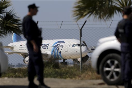 Police officers stand guards by the fence of the airport as a hijacked EgyptAir aircraft is seen after landing at Larnaca Airport in Cyprus Tuesday, March 29, 2016. The EgyptAir plane was hijacked on Tuesday while flying from the Egyptian Mediterranean coastal city of Alexandria to the capital, Cairo, and later landed in Cyprus where some of the women and children were allowed to get off the aircraft, according to Egyptian and Cypriot officials. (AP Photo/Petros Karadjias)