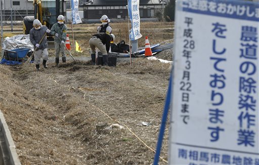 In this Feb. 24, 2016 photo, workers clean a farm road during their decontamination work in Minamisoma, Fukushima Prefecture, northeastern Japan. Some 7,000 day laborers are cleaning up this irradiated town just north of the Fukushima nuclear plant, wiping roof tiles and removing soil and plants in a seemingly never-ending battle against winds that bring fresh contamination. (AP Photo/Shizuo Kambayashi)