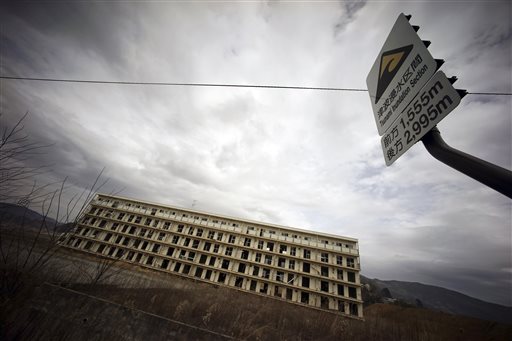 In this Monday, March 7, 2016 photo, the ruin of a residential building damaged by the March 11, 2011 earthquake and tsunami still stands near the sign of a tsunami inundation section in Rikuzentakata, Iwate Prefecture. The five-story building is one of legacies that still stand in northern Japan’s coastal towns, five years after the disaster that killed more than 18,000 people. (AP Photo/Eugene Hoshiko)