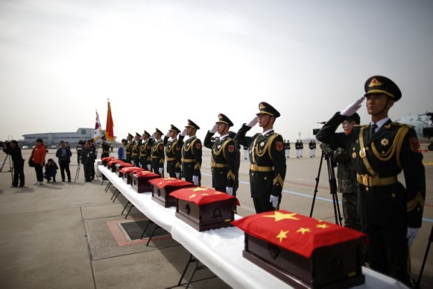 Chinese honor guards salute caskets containing the remains of Chinese soldiers with Chinese national flags during a handing over ceremony of the remains at the Incheon International Airport in Incheon on March 31, 2016. Coffins carrying the remains of 36 soldiers -- excavated by South Korea's Defence Ministry from March to November last year -- were flown from Incheon airport to the northeastern city of Shenyang, where China has a state cemetery for its war dead. / AFP / POOL / KIM HONG-JI