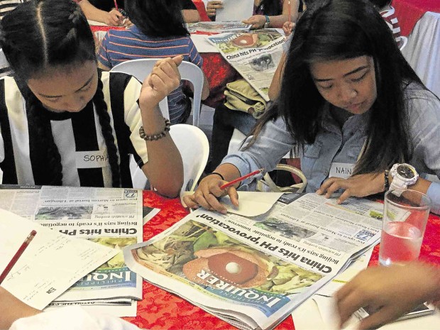STUDENTS carefully scan the Inquirer’s front page in the game of scavenger hunt.