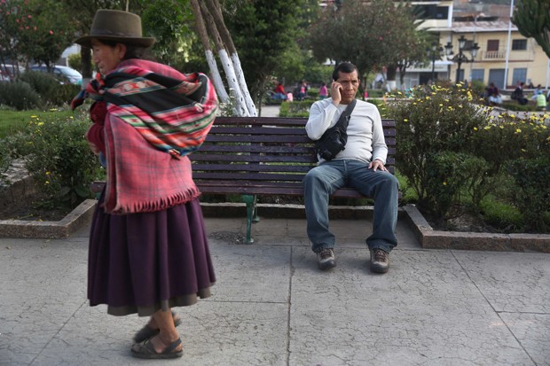 In this Nov. 6, 2015 photo, narcotics police Sgt. Johnny Vega talks on his cellphone while he sits on the same park bench where he was shot by a gunman in Talavera, Peru. Vega, 45, had his colon reattached in June but remains disabled. If he doesn't mend by August, he faces forced retirement. (AP Photo/Martin Mejia)