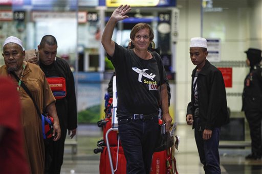 American adventurer Blaine Gibson, center, waves as he arrives at the Kuala Lumpur International Airport in Sepang, Malaysia, Saturday, March 5, 2016.  Gibson said Saturday that it would be a "very lucky discovery" if the piece of aircraft he found on a sandbank off the coast of Mozambique is confirmed to be from the Malaysia Airlines jet that vanished two years ago. (AP Photo/Joshua Paul)