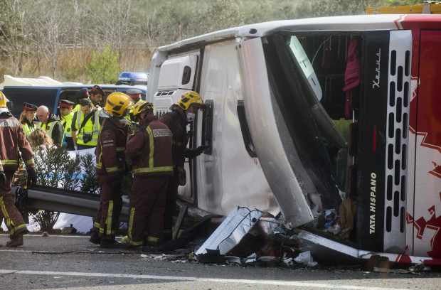 Emergency services personnel stand at the scene of a bus accident crashed on the AP7 highway that links Spain with France along the Mediterranean coast near Freginals halfway between Valencia and Barcelona early Sunday, March 20, 2016. A bus carrying university students back from a fireworks festival crashed Sunday on a main highway in northeastern Spain, killing 14 passengers and injuring 30 others, a Catalonian official said. (AP Photo)