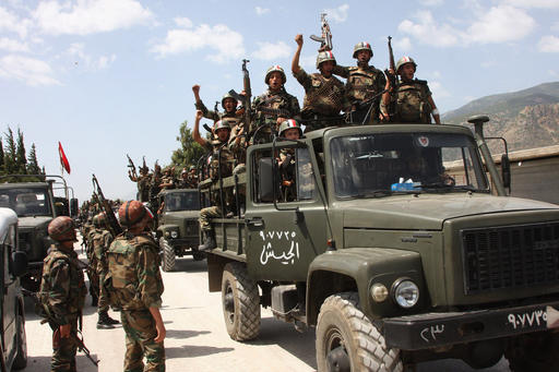FILE - In this file photo taken on Friday, June 10, 2011, during a government organized tour for the media, shows Syrian army soldiers standing on their military trucks chanting slogans in support of Syrian President Bashar Assad, as they enter a village near the town of Jisr al-Shughour, north of Damascus, Syria. (AP Photo, File)