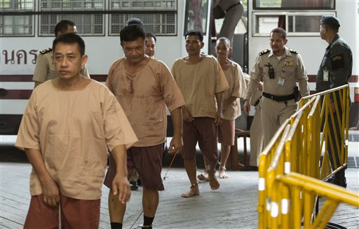 Prisoners are escorted by Thai correction officers from a bus to the Criminal Court on their arrival at the Criminal Court in Bangkok, Thailand, Tuesday, March 15, 2016. Prosecutors in Thailand have called their first witnesses in a major human trafficking trial with 92 defendants, including a senior army officer, implicated in smuggling, kidnappings and the deaths of dozens of people. The case came to light after more than 30 bodies were discovered last year in shallow graves in southern Thailand, exposing networks that trafficked Rohingya Muslims fleeing persecution in Myanmar and held them for ransom in jungle camps. (AP Photo/Mark Baker)