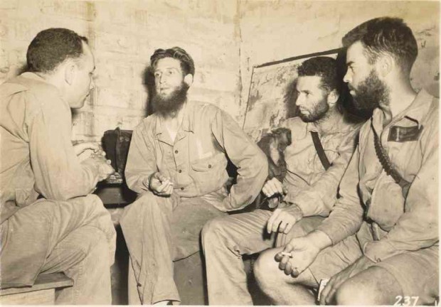 SGT. ALFRED D. BRUCE (center) being interviewed by an American intelligence officer. On the right are two naval aviators who were rescued by Aeta Squadron 30 after they were shot down over Clark Field.