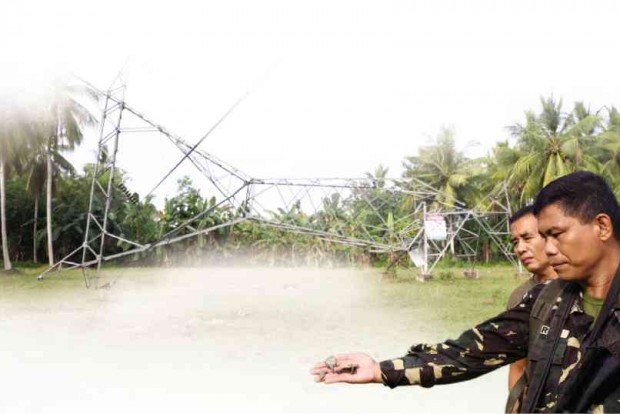 A GOVERNMENT soldier holds fragments of the bomb that toppled this electric transmission tower on Jan. 13, 2015, in Pagalungan town, Maguindanao province. The firm that maintains the transmission facilities is currently embroiled in a right-of-way conflict involving parcels of land where its towers stand. FERDINAND CABRERA/CONTRIBUTOR