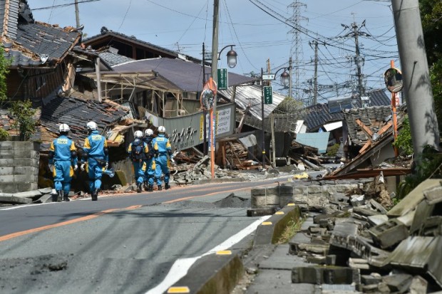 Policemen search for missing persons amongst homes destroyed in the recent earthquakes in Mashiki in Kumamoto prefecture on April 17, 2016. Rescuers were racing against the weather and the threat of more landslides on April 17 to reach people still trapped by two big earthquakes that hit southern Japan and killed at least 41. / AFP PHOTO / KAZUHIRO NOGI