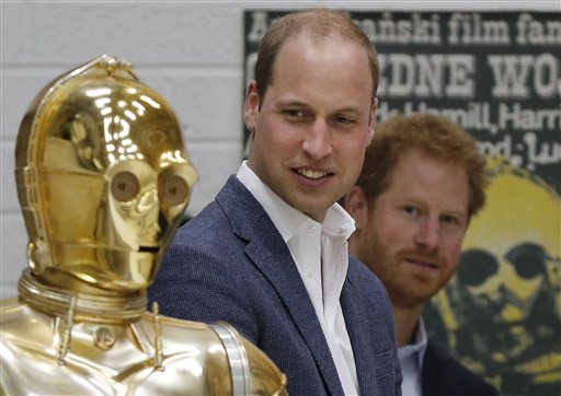Britain Prince William, centre and, Britain's Prince Harry look at  Star Wars character  the droid C3P0 as they visit the creature and droid department at Pinewood studios in Iver Heath, west of London on Tuesday  April 19, 2016. Prince William,  and Prince Harry are touring Pinewood to visit the production workshops and meet the creative teams working behind the scenes on the Star Wars films. (Adrain Dennis, Pool Via AP)