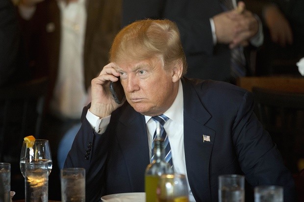 In this Feb. 18, 2016 file photo, Republican presidential candidate Donald Trump listens to his mobile phone during a lunch stop in North Charleston, S.C. Trump's approach to Twitter has been as unorthodox as his presidential campaign. The billionaire's use of the social media service has been unpredictable and unfiltered, sometimes brilliant and occasionally typographically challenged. He has celebrated the support of scores of accounts that appear almost solely dedicated to him. AP FILE PHOTO