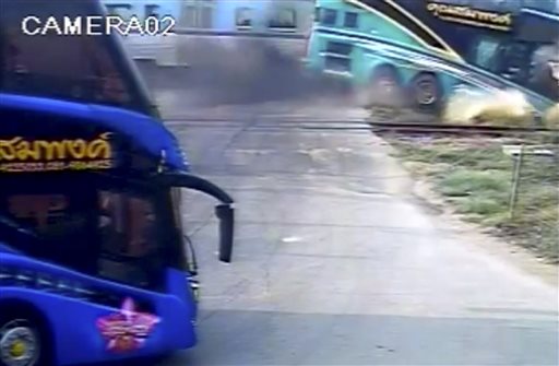 This image taken from close circuit television video provided by TPBS shows the moment a passenger train, left in background, hit a tourist bus, right, at a crossing in Nakhon Pathom province, west of Bangkok, Thailand, Sunday, April 3, 2016. The accident occurred at about 7:30 a.m. when the double-decker bus was taking Thai tourists to Samet island in Rayong province, southeast of Bangkok. (TPBS via AP) THAILAND OUT, TV OUT, NO SALES