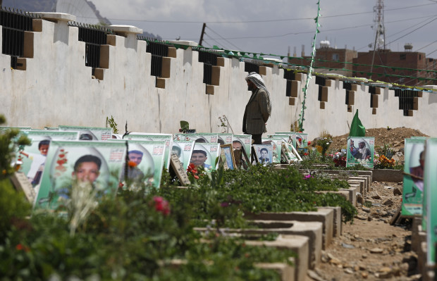 A Shiite rebel Houthi stands among the portrait adorned graves of  Houthi fighters and supporters who were killed in the ongoing conflict in Yemen, a few hours before the start of a fresh cease-fire, in Sanaa, Yemen, Sunday, April 10, 2016. (AP Photo/Hani Mohammed)
