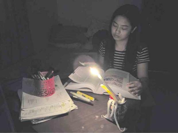 IGNORING the sweltering heat, a medical student reads her textbooks illuminated only by candlelight as Davao City goes through daily brownouts that now last five hours.        KARLOS MANLUPIG/INQUIRER MINDANAO