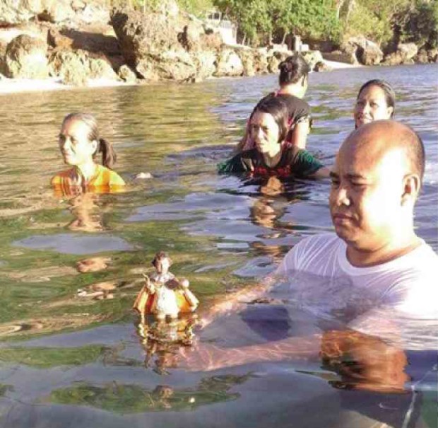 FR. ROMEO Desuyo, parish priest of the Birhen de los Remedios parish in the island village of Odlot in Bogo City, puts an image of the Sto. Niño in the sea off the shores of Odlot in a ritual that started at least 600 years ago and has been revived as a punishing drought brought by El Niño continues to ravage the province and city of Cebu. CONTRIBUTED PHOTO