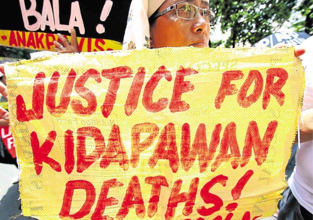 A POSTER demanding charges be filed against policemen who opened fire at the rally of farmers in Kidapawan City is displayed during a protest rally by militant groups at the Department of Justice. RICHARD REYES
