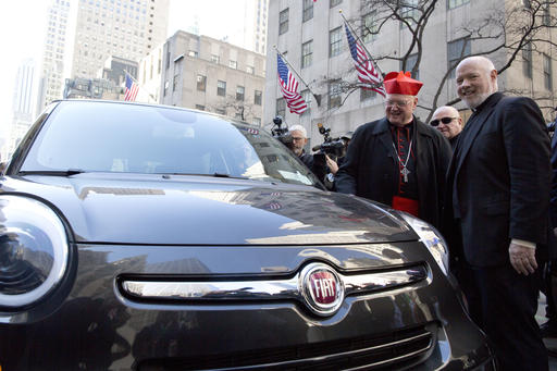 Cardinal Timothy Dolan, left, and Catholic Charities Msgr. Kevin Sullivan inspect the Fiat 500 sedan used during the visit of Pope Francis to New York as it makes a stop in front of St. Patrick's Cathedral during the St. Patrick's Day parade.  AP Photo