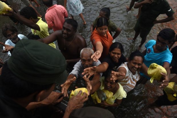 The Sri Lankan army distributes food to flood victims in Kelaniya, on the outskirts of Colombo on May 22, 2016.  Sri Lankan soldiers pulled more bodies from landslides and distributed food and water to hundreds of thousands of residents camped in shelters on May 22 after major floods hit the island. More than 80 people are known to have died so far across the island amid fears the number could rise -- with 118 people still listed as missing. / AFP PHOTO / ISHARA S.KODIKARA