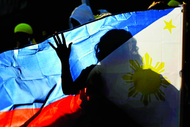 RALLYING TO THE FLAG A member of a dance group holds up the Philippine flag at the start  of the Liberal Party’s “miting de avance” at Quezon Memorial Circle on Saturday night.  President Aquino and his Cabinet joined LP standard-bearer Mar Roxas and running mate Camarines Sur Rep. Leni Robredo in their last rally before Monday’s elections. RAFFY LERMA 