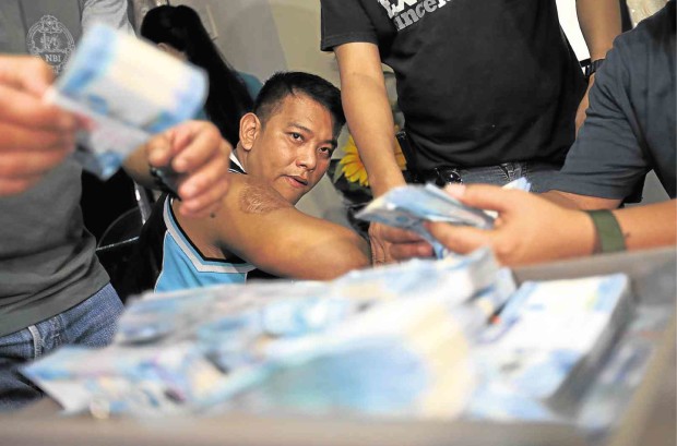 PO2 Jolly Aliangan was caught keeping a stash of “shabu,” P7 million in cash, several firearms,  and fake vehicle license plates when NBI agents raided his Manila residence on Wednesday.  photos by EDWIN BACASMAS 