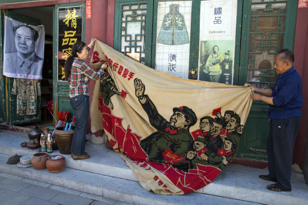 Vendors unfurl a banner from 1969 depicting former Chinese leader Mao Zedong as he "inspects the great army of the Cultural Revolution" and the slogan "Navigating the seas depends on the helmsman" at a curio market in Beijing, China, Monday, May 16, 2016. Exactly 50 years ago, China embarked on what was formally known as the Great Proletarian Cultural Revolution, a decade of tumult launched by Mao Zedong to revive communist goals and enforce a radical egalitarianism. The milestone was largely ignored Monday in the Chinese media, reflecting continuing sensitivities about a period that was later declared a "catastrophe." (AP Photo/Ng Han Guan)