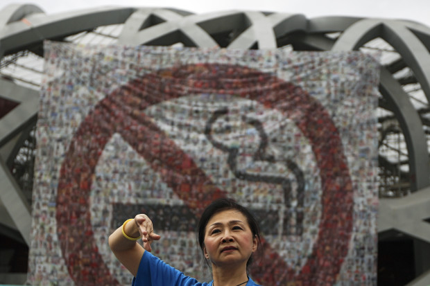 A woman performs in front of anti-smoking banners displayed on the Bird's Nest stadium to mark the World No Tobacco Day in Beijing, China, Tuesday, May 31, 2016. Beijing celebrated the World No Tobacco Day on Tuesday, one year since the Chinese capital imposed a smoking ban in all indoor public places. With about 315 million smokers, China is the world's biggest producer and consumer of tobacco products. And roughly 700 million people are routinely exposed to second-hand smoke, according to the WHO. (AP Photo/Andy Wong)