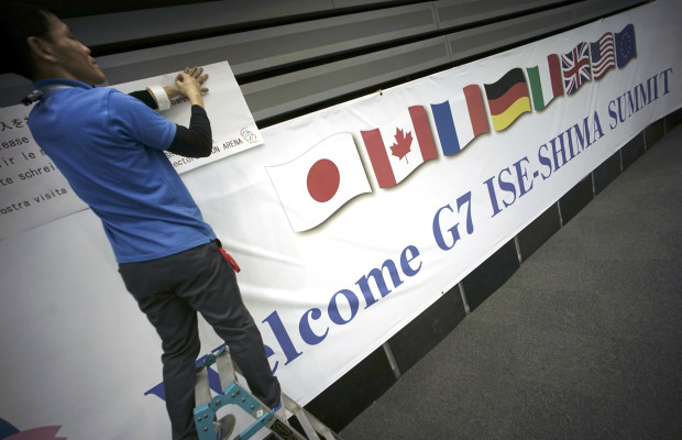 FILE - In this May 24, 2016 file photo, a man puts a banner of the G7 Summit at International Media Center in Ise, Mie Prefecture, central Japan. Leaders of the Group of Seven rich nations will undoubtedly voice unity over fighting terrorism, pandemics and tax evasion at their summit in Japan starting on Thursday, May 26. Finding a consensus on how to breathe life into their sluggish economies is proving more elusive. (AP Photo/Eugene Hoshiko, File)