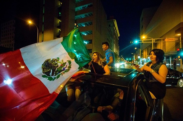 A woman waves the Mexican flag while driving past the Albuquerque Convention Center after a rally by Republican presidential candidate Donald Trump, Tuesday, May 24, 2016, in Albuquerque, N.M. JETT LOE/THE LAS CRUCES SUN-NEWS VIA AP