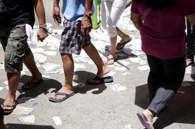 People walk on a pile of sample ballots. Photo by Tristan Tamayo/INQUIRER.net