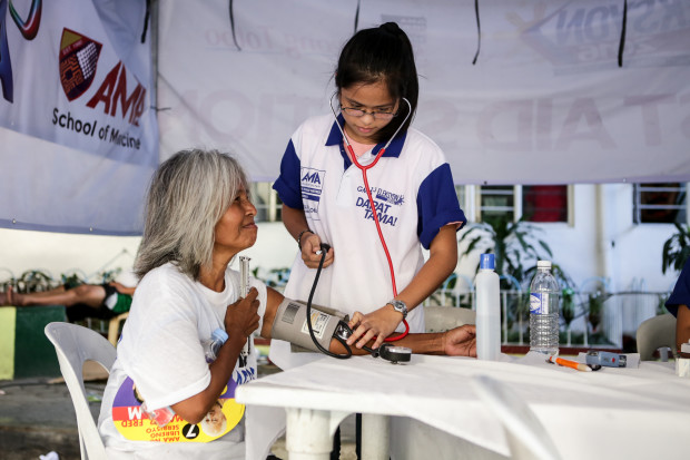 A volunteer nurse assists the elderly for free BP check at Rosauro Almario Elementary School. Photo by Tristan Tamayo/INQUIRER.net