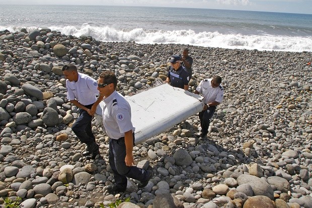In this July 29, 2015, file photo, French police officers carry a piece of debris from a plane known as a flaperon in Saint-Andre, Reunion Island. The barnacle-encrusted part was the first trace of Malaysia Airlines Flight 370 that disappeared two years ago. Malaysia's confirmation on Thursday, May 12, 2016, that other debris found in March 2016 came from missing Malaysia Airlines Flight 370 brings to five the number of parts that have been recovered from the aircraft that vanished two years ago. AP FILE PHOTO