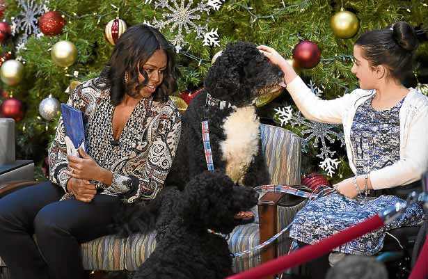 WHITE HOUSE CELEBS In thisDec. 14, 2015, photo, US first lady Michelle Obama, with Bo beside her, and Luna Fera, 11, do a reading of “Twas the Night Before Christmas” to a group of children at the Children’s National Health System inWashington. At their feet is Sunny. AP