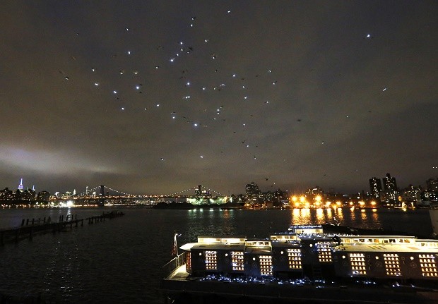 Some of the 2,000 pigeons wearing LED lights fly in the night sky over the Manhattan's East River after they were released from their coops on board the Baylander, lower right, a decommissioned naval ship docked at the Brooklyn Navy Yard, Thursday, May 5, 2016, in New York. The 30-minute performance was part of artist Duke Riley's "Fly By Night" creation. The Manhattan skyline can be seen in the distance, left. AP 