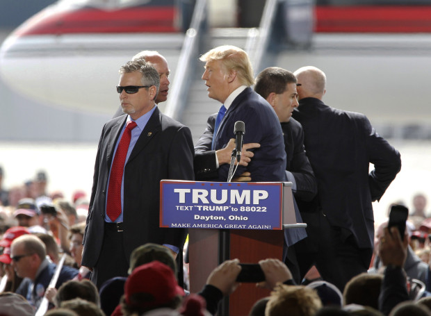 FILE - In this March 12, 2016, file photo, security personnel surround Republican presidential candidate Donald Trump after a man rushed the stage during a campaign rally at the Wright Brothers Aero Hangar at Dayton International Airport in Vandalia, Ohio. Thomas DiMassimo, a 22-year-old Wright State University student, has pleaded not guilty to a misdemeanor charge of illegally entering a restricted area. During a Wednesday, April 27, 2016, status conference, participants told Magistrate Sharon Ovington that no agreement has been reached yet to avoid a trial scheduled May 31, 2016. (Lisa Powell/Dayton Daily News via AP, File) LOCAL PRINT OUT; LOCAL TELEVISION OUT; WKEF-TV OUT; WRGT-TV OUT; WDTN-TV OUT; MANDATORY CREDIT