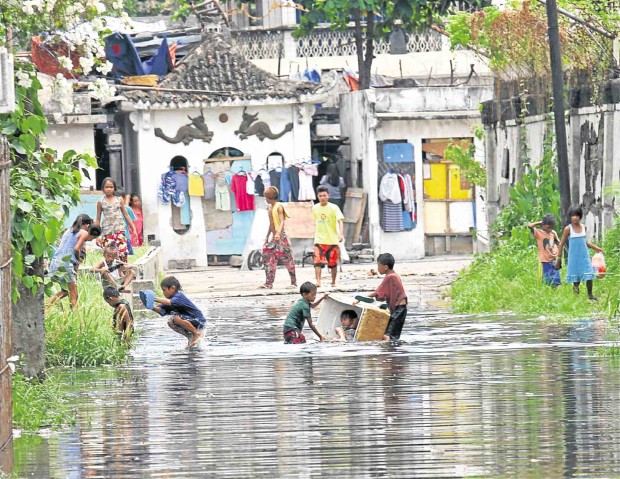 CHILDREN living inside a slum in the Ludo Cemetery in Barangay Carreta in Cebu City play in floodwater following heavy rains on Wednesday that marked the start of the rainy season in the city.           JUNJIE MENDOZA/CEBU DAILY NEWS