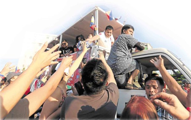 PEOPLE watching a motorcade of Duterte pass by in Pasay City reach out to the now presumptive President-elect as he hands out bottles of water and tries to shake the hands of spectators. GRIG C. MONTEGRANDE