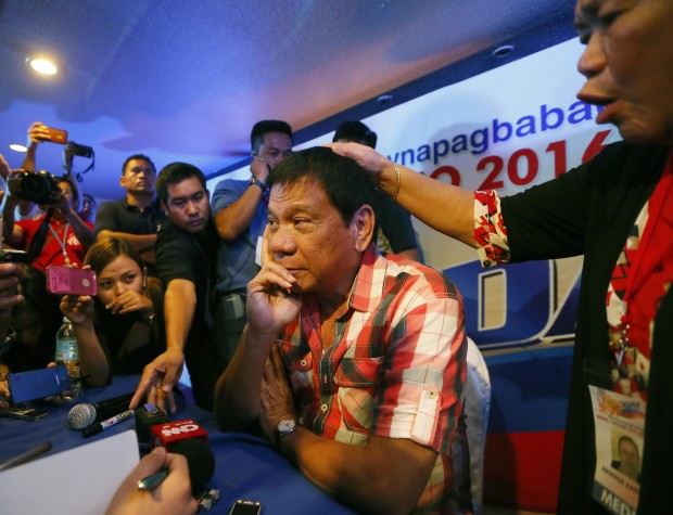 Front-running presidential candidate Mayor Rodrigo Duterte is prayed over by a supporter during a news conference shortly after voting in a polling precinct at Daniel R. Aguinaldo National High School, Matina district, his hometown in Davao city in southern Philippines Monday, May 9, 2016. Duterte was the last to vote among five presidential hopefuls. (AP Photo/Bullit Marquez)