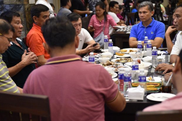 This photo taken on May 15, 2016 shows Philippines' president-elect Rodrigo Duterte (L, in black) gesturing as he talks with military and police officials during an informal meeting at a hotel in Davao City, in the southern island of Mindanao. Business titans, turncoat politicians, celebrities and rebel leaders are descending on the long-neglected far southern Philippines, hoping to gain favour with the nation's shock new powerbroker. The remote and dusty city of Davao has suddenly become the country's new seat of power after hometown hero Rodrigo Duterte won last week's presidential election in a landslide. / AFP PHOTO / TED ALJIBE / TO GO WITH AFP STORY PHILIPPINES-POLITICS-DUTERTE-DAVAO BY AYEE MACARAIG