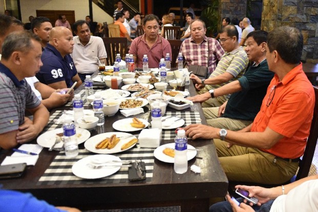 This photo taken on May 15, 2016 shows Philippines' president-elect Rodrigo Duterte (2nd R) talking with military and police officials during an informal meeting at a hotel in Davao City, in the southern island of Mindanao. Business titans, turncoat politicians, celebrities and rebel leaders are descending on the long-neglected far southern Philippines, hoping to gain favour with the nation's shock new powerbroker. The remote and dusty city of Davao has suddenly become the country's new seat of power after hometown hero Rodrigo Duterte won last week's presidential election in a landslide. / AFP PHOTO / TED ALJIBE / TO GO WITH AFP STORY PHILIPPINES-POLITICS-DUTERTE-DAVAO BY AYEE MACARAIG